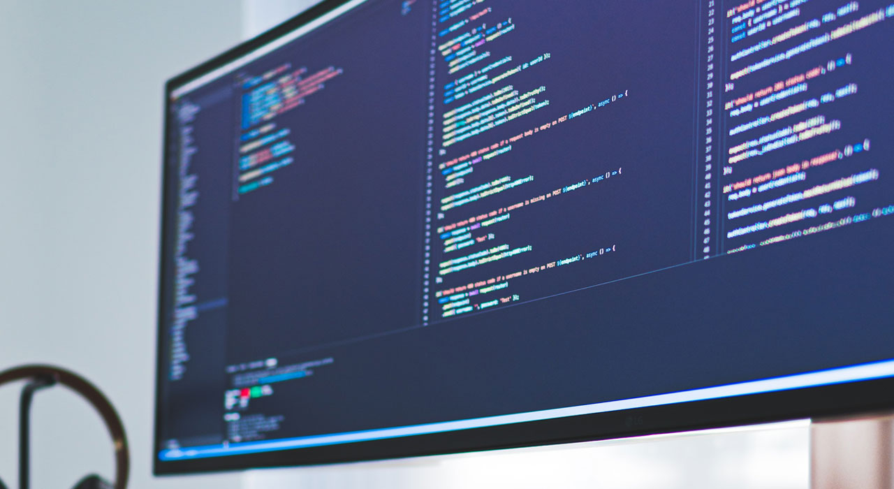Close-up of a computer monitor displaying lines of colorful code on a dark background